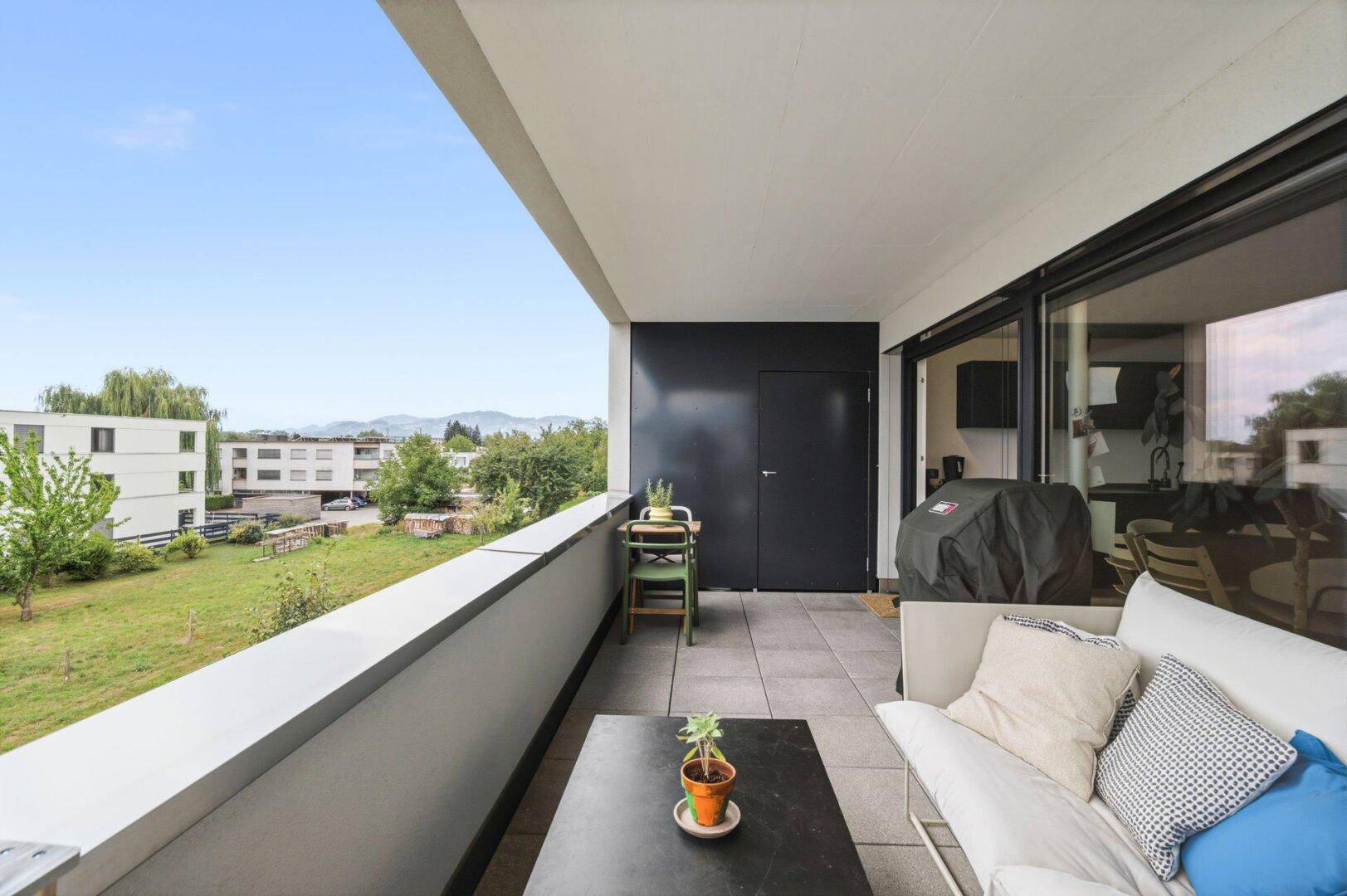 Geräumiger Balkon mit Sitzgelegenheiten, Grill und Blick ins Grüne.