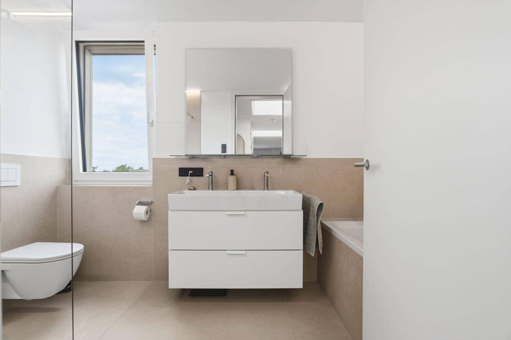 Modernes Badezimmer mit Waschtisch, Wand-WC und Badewanne.