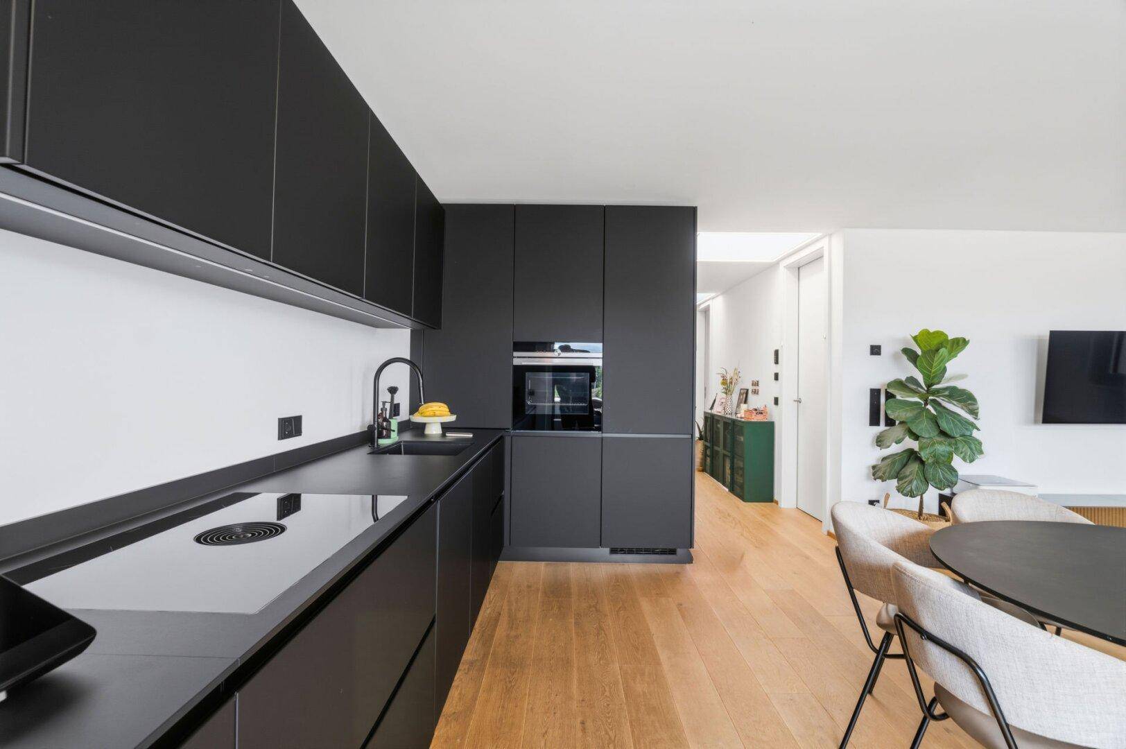 Hochwertige schwarze Einbauküche mit Induktionskochfeld und integriertem Backofen.