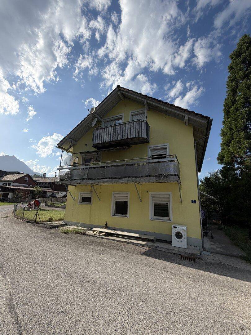 Ansicht eines gelben Wohnhauses mit mehreren Balkonen und einer Waschmaschine im Außenbereich.