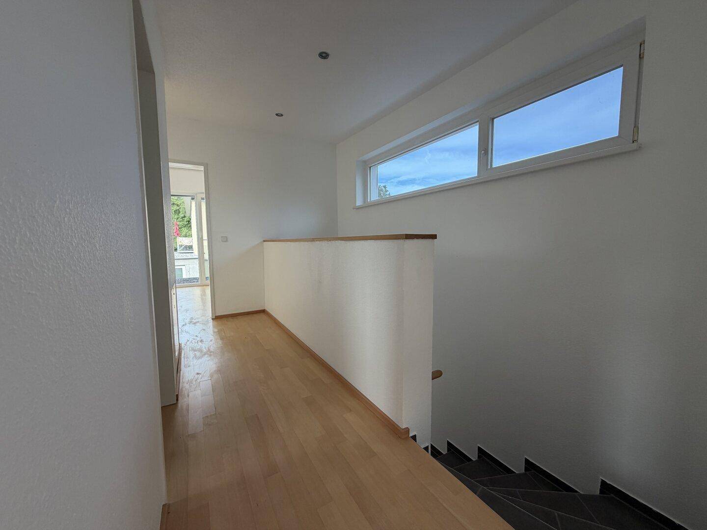 Geräumiger Flur im Obergeschoss mit Holzboden und breitem Fenster.