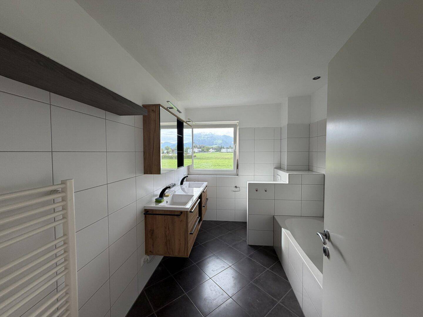 Geräumiges modernes Badezimmer mit Doppelwaschbecken, Badewanne und beheiztem Handtuchhalter.