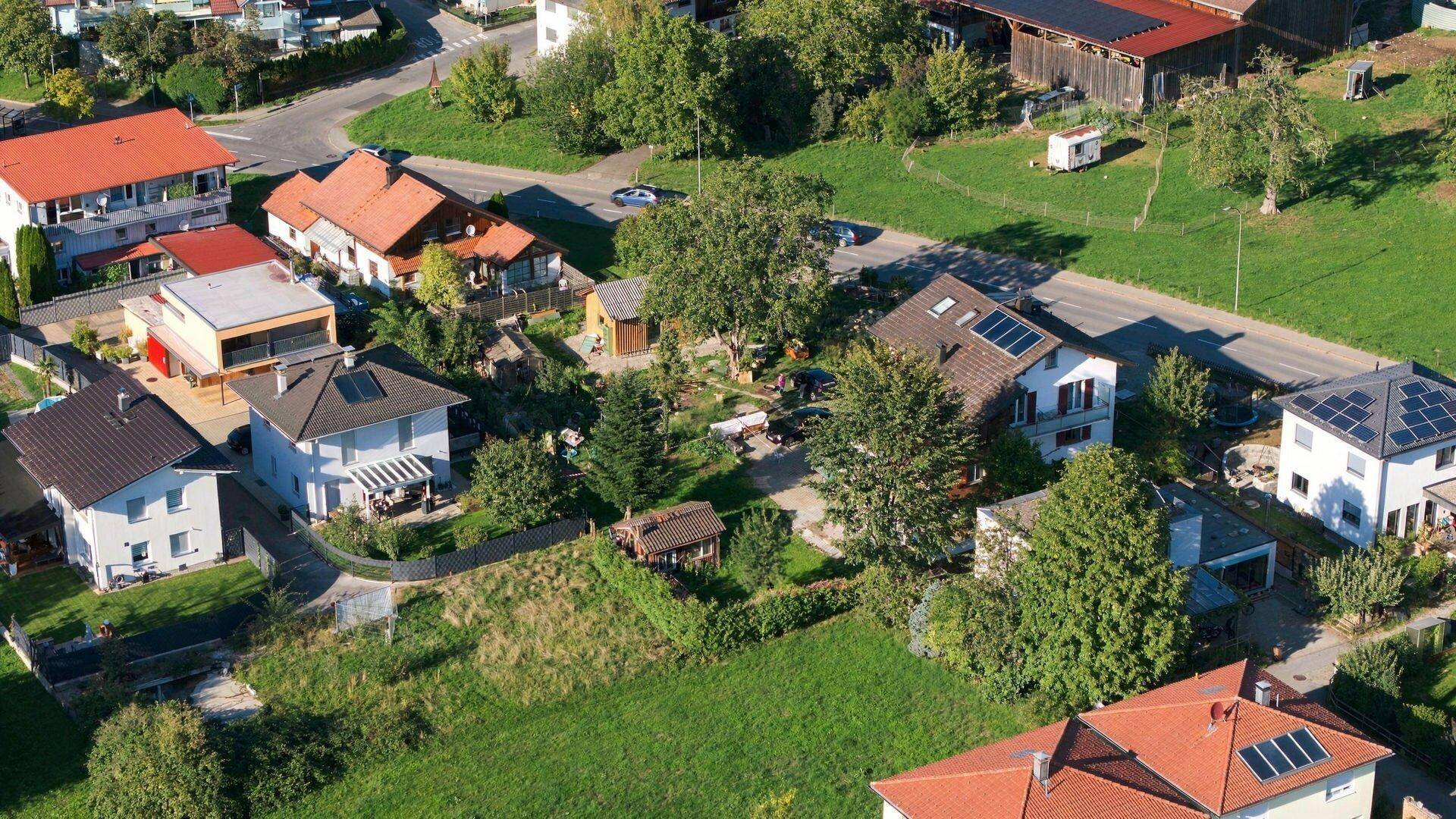 Luftaufnahme einer Wohnsiedlung mit Einfamilienhäusern, viel Grün und einigen Dächern mit Solaranlagen.