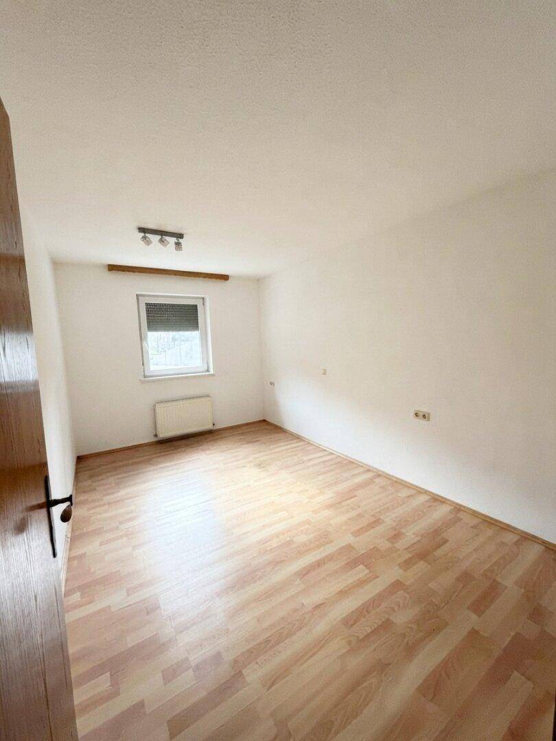 Geräumiges Zimmer mit Laminatboden und einem Fenster, das für natürliche Belüftung sorgt.