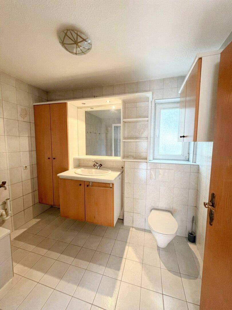 Badezimmer mit Fliesenboden, Einzelwaschbecken und einem Spiegelschrank über dem Waschtisch.