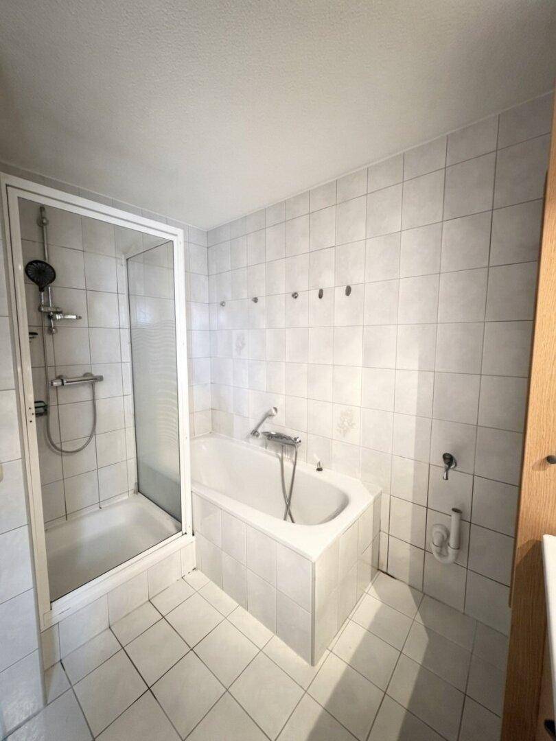 Gefliestes Badezimmer mit Badewanne und separater Duschkabine, ideal für den täglichen Gebrauch.