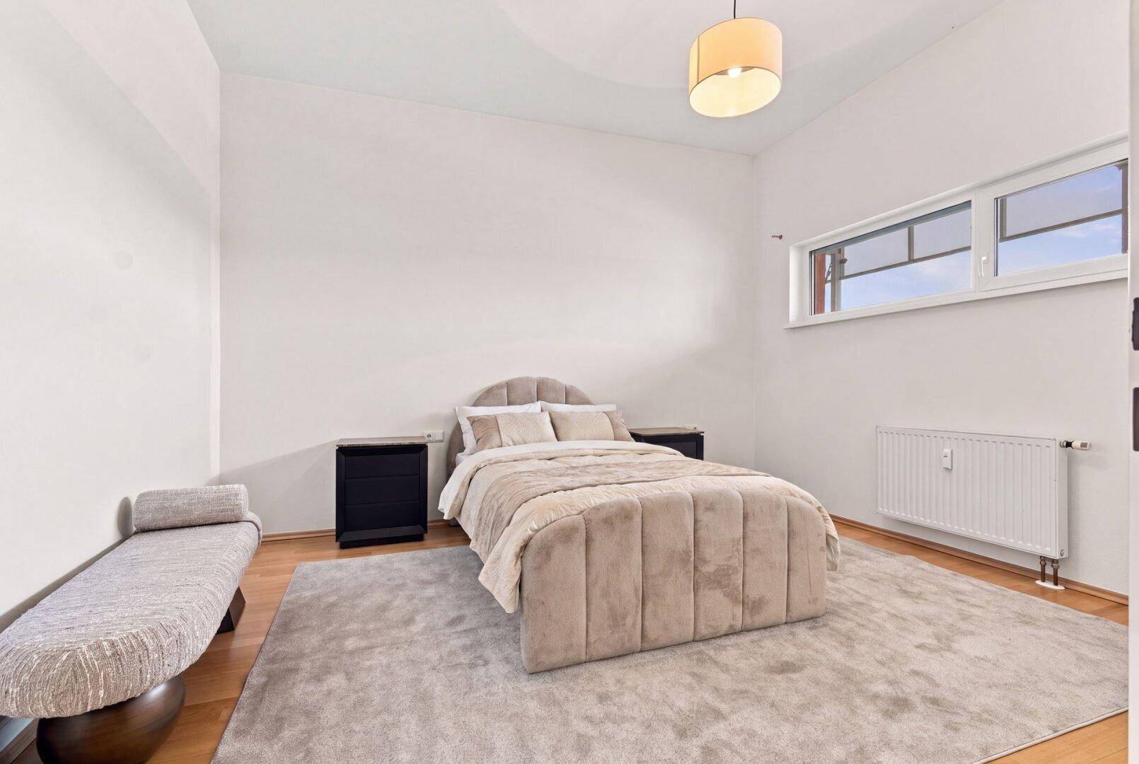 Ruhiges Schlafzimmer mit beigem Bett, Nachttischen und einem Fenster für natürliches Licht.