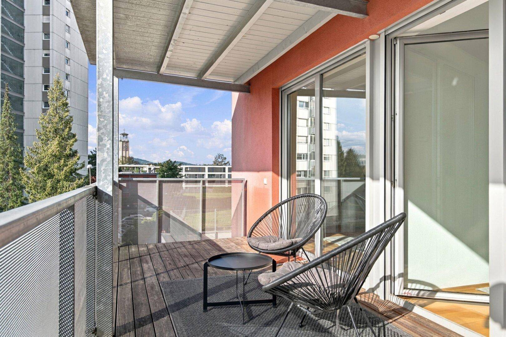Gemütlicher Balkon mit modernen Sitzmöbeln und einem kleinen Tisch, ideal zum Entspannen.