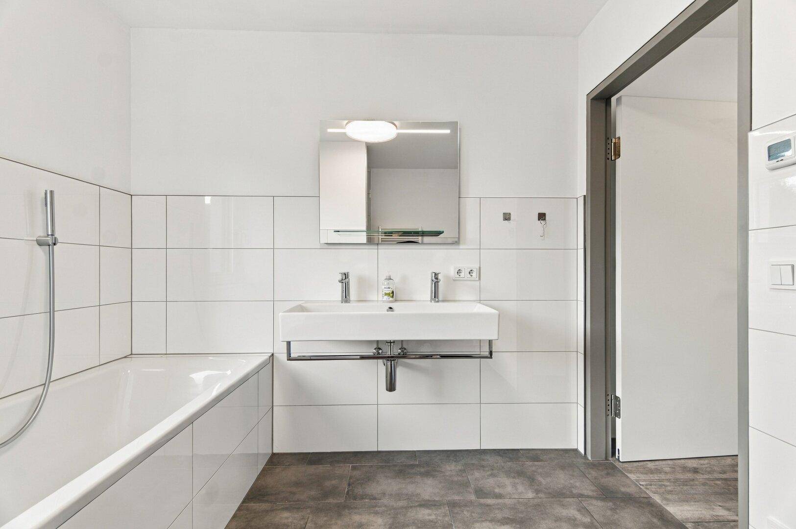 Modernes Badezimmer mit Badewanne, Einzelwaschbecken und Spiegelschrank.