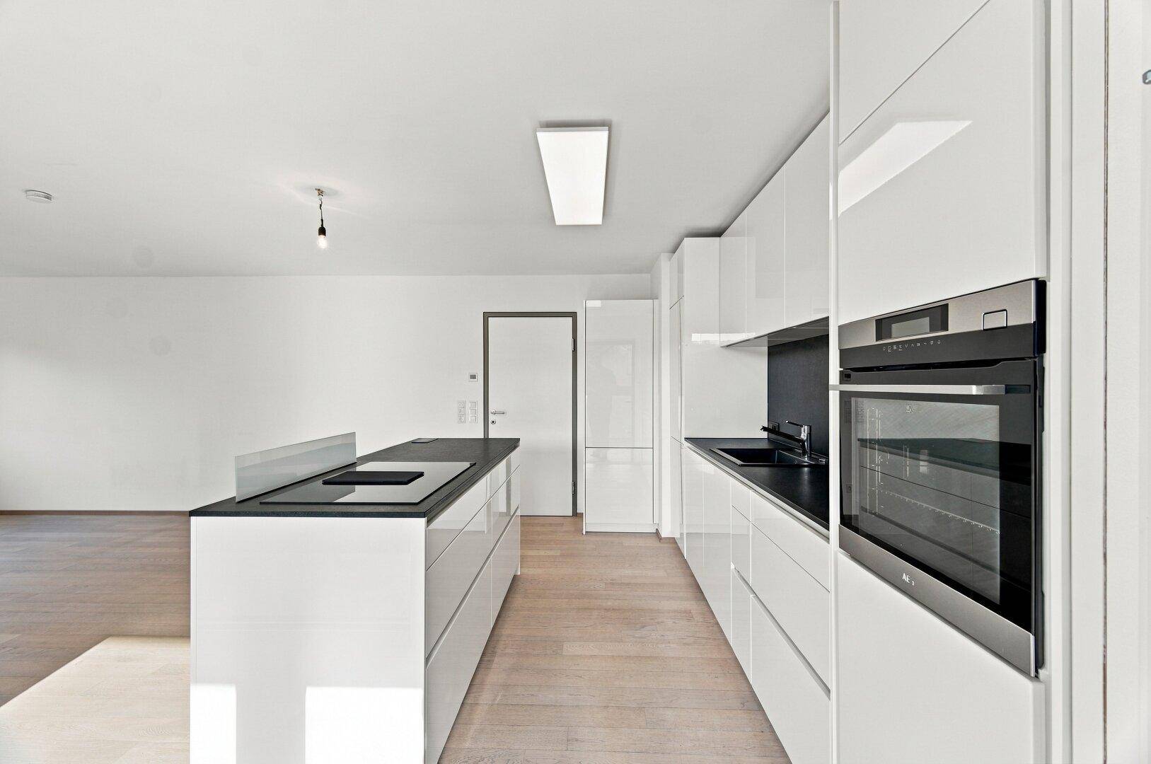 Moderne Küche mit weißer Hochglanzfront, Kücheninsel und integrierten Geräten.