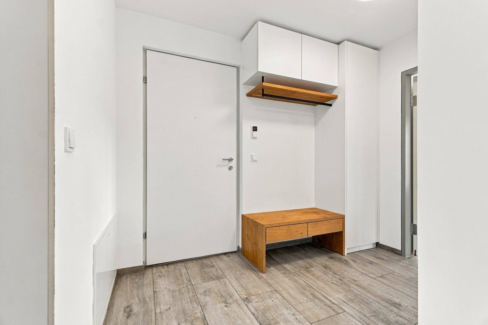 Heller Eingangsbereich mit Holzboden, Garderobe und Sitzbank.