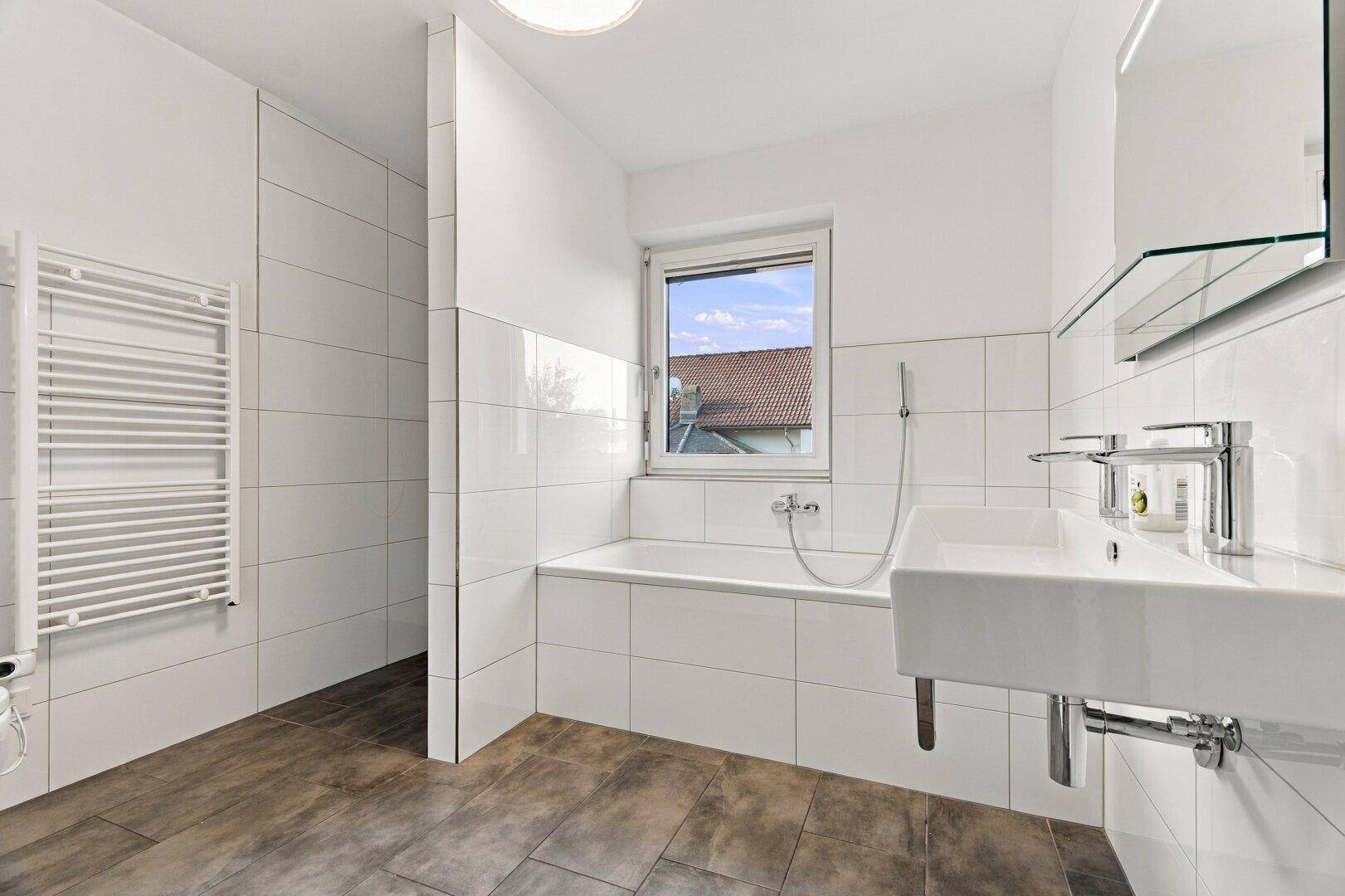 Modernes Badezimmer mit Badewanne, Dusche, Einzelwaschbecken und Fenster.