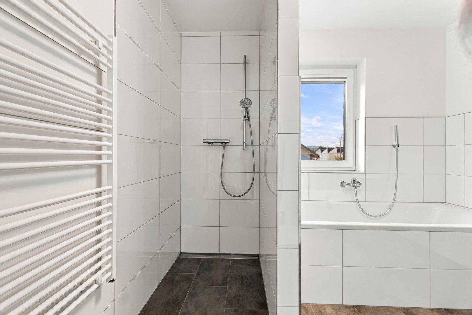 Modernes Badezimmer mit ebenerdiger Dusche, Badewanne und beheiztem Handtuchhalter.