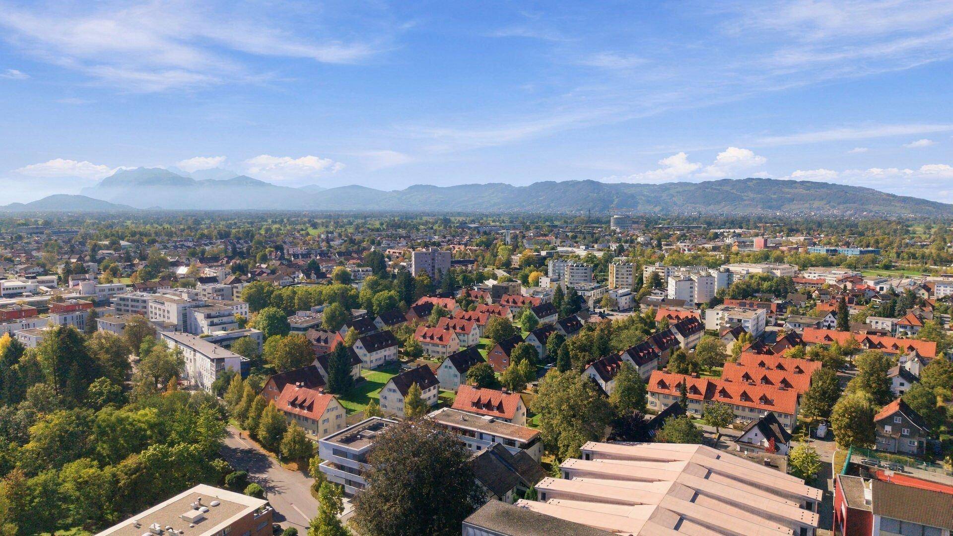 Weitwinkelaufnahme einer Stadt mit ausgedehnten Wohngebieten und fernen Bergen.