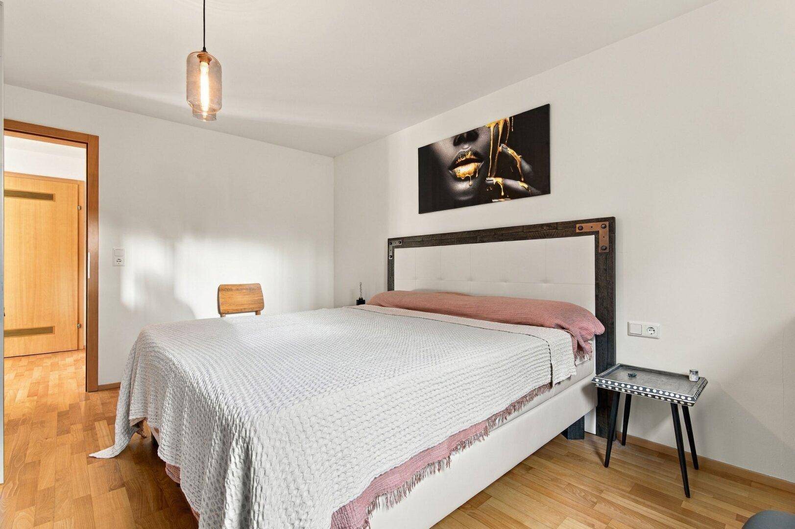 Helles Schlafzimmer mit Holzboden und modernem Bettgestell.
