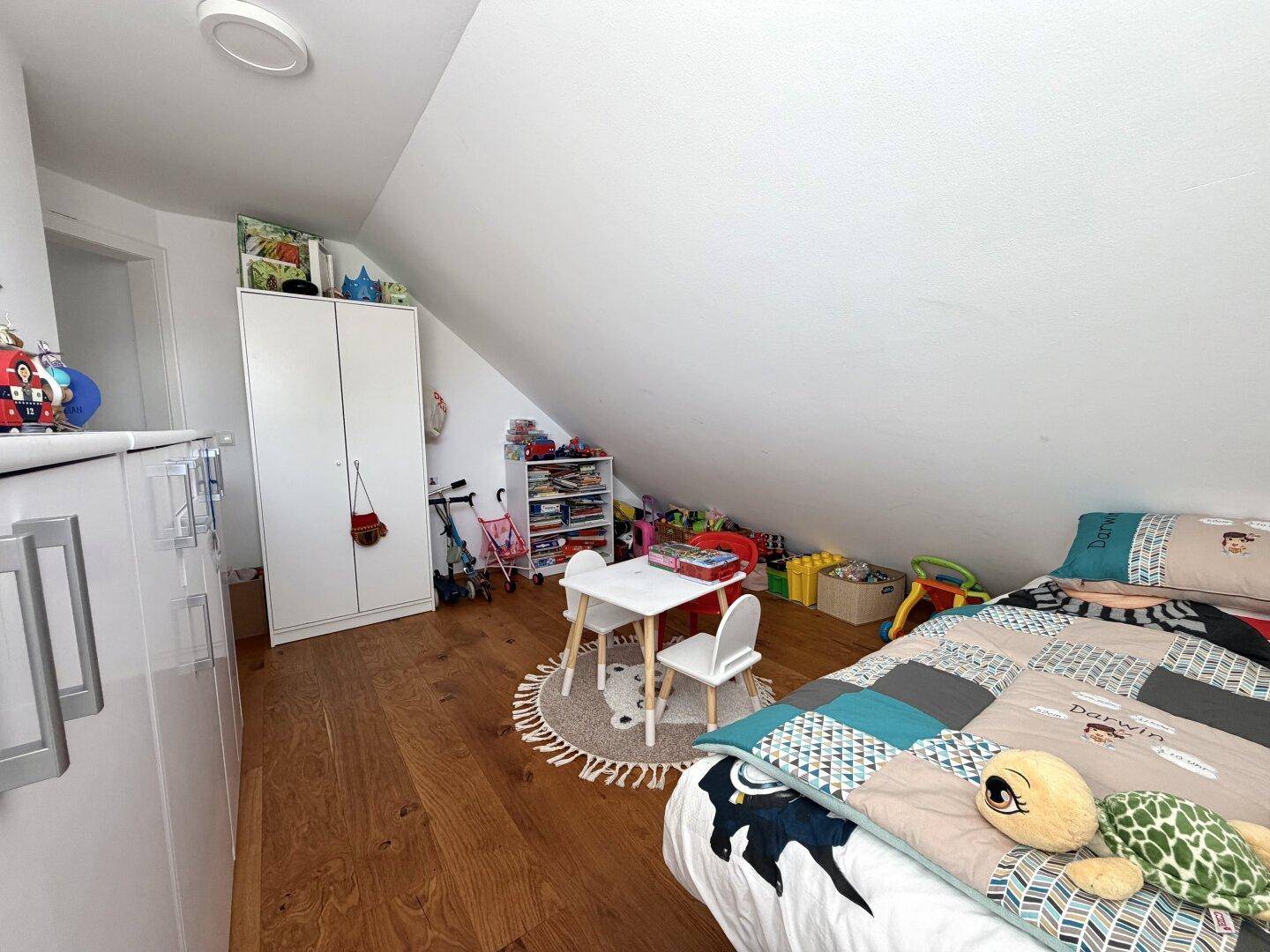 Kinderzimmer mit Holzboden, Spielbereich und Dachschräge, hell und freundlich eingerichtet.