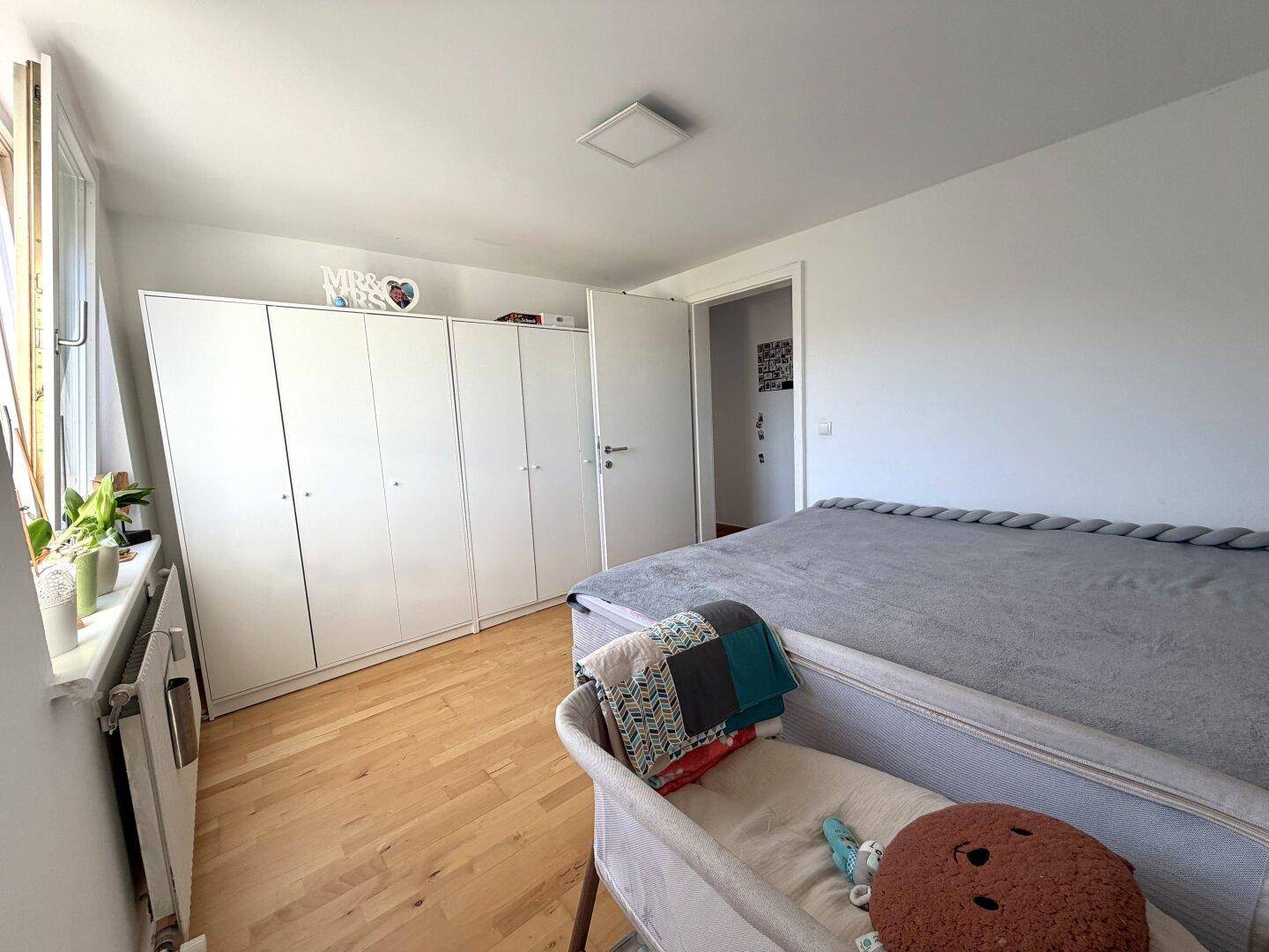 Geräumiges Schlafzimmer mit großem Bett, weißen Kleiderschränken und hellem Holzboden.