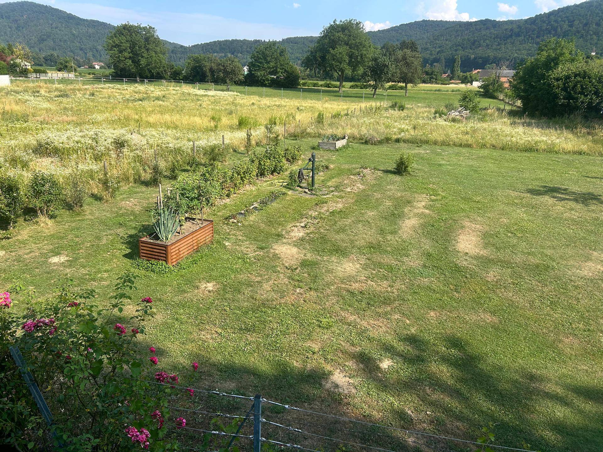 Gepflegter Nutzgarten mit Hochbeeten und weitem Blick auf die umliegende Naturlandschaft.