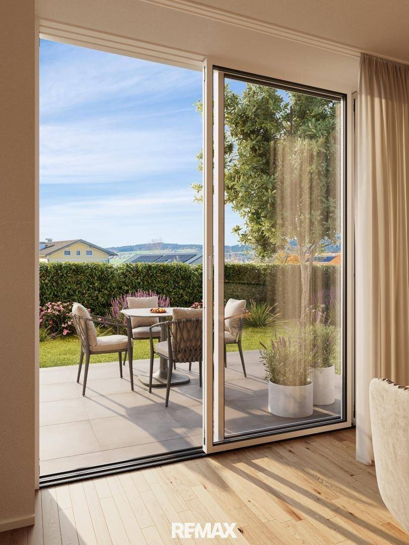Große Glasschiebetür bietet Zugang zu einer möblierten Terrasse mit Blick ins Grüne.