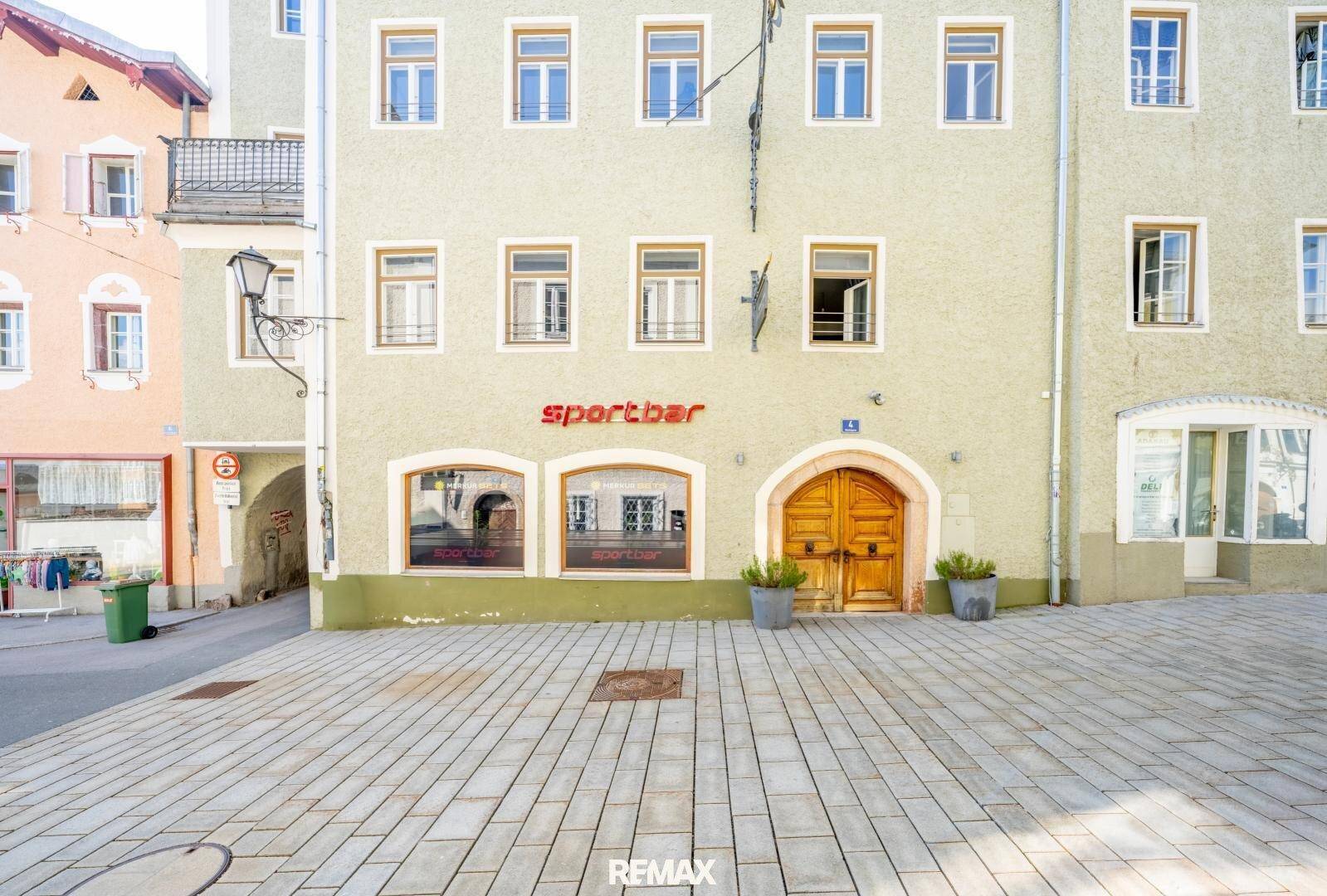 Historische Fassade eines Gebäudes mit großen Fenstern und dem Schriftzug 'Sportbar'.