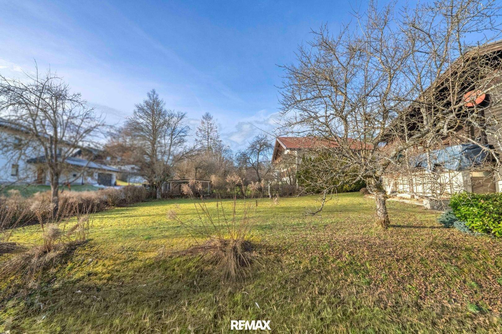 Weitläufiger Gartenbereich mit Rasen, Bäumen und Blick auf die umliegende Landschaft.