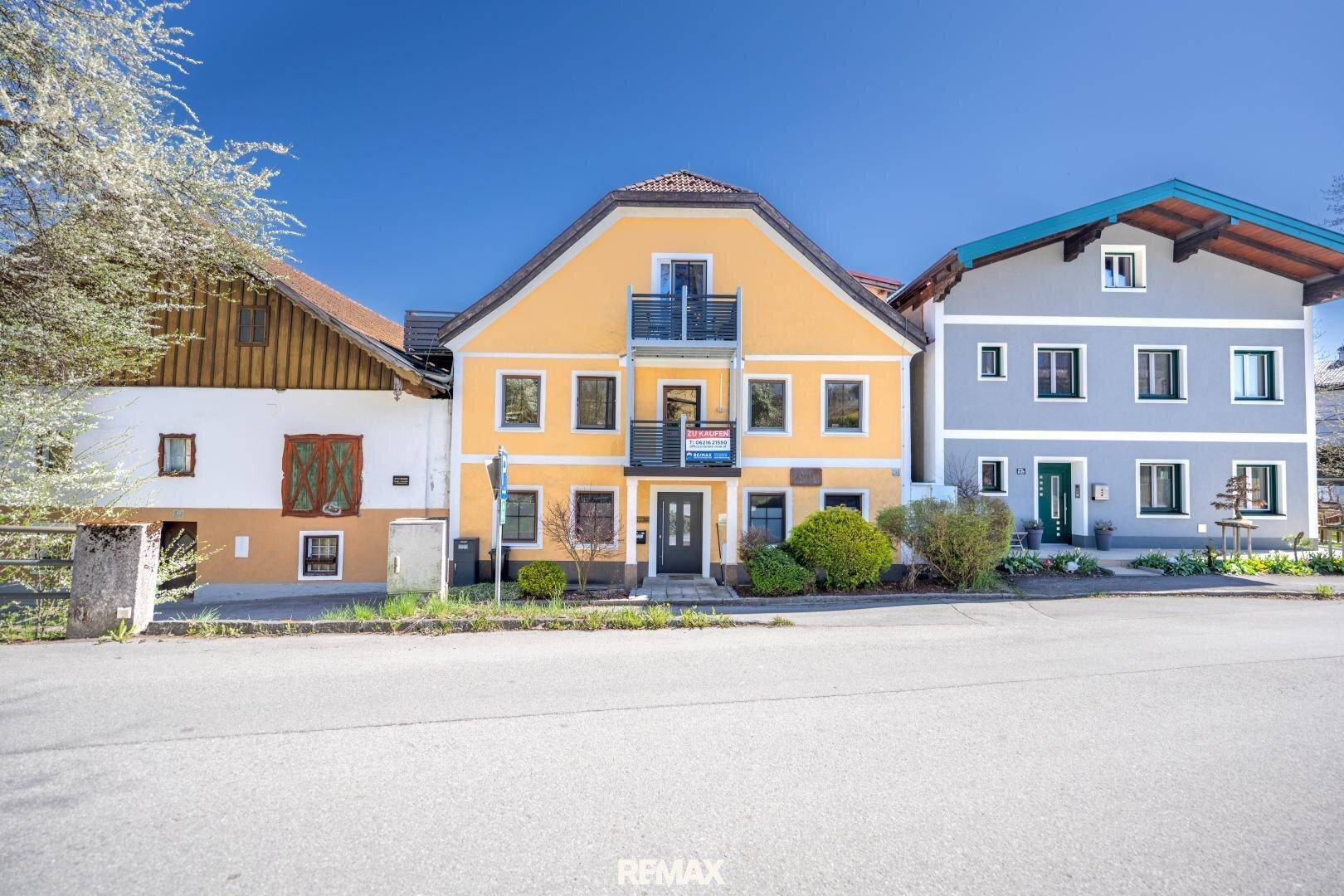 Gelbes Mehrfamilienhaus mit mehreren Balkonen und traditioneller Architektur an einer Straße gelegen.