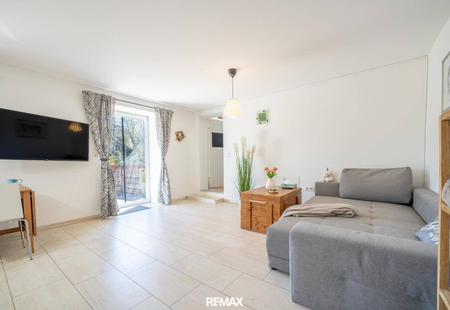 Gemütliches Wohnzimmer mit Sofa, Holztisch und Zugang zu einem Außenbereich.