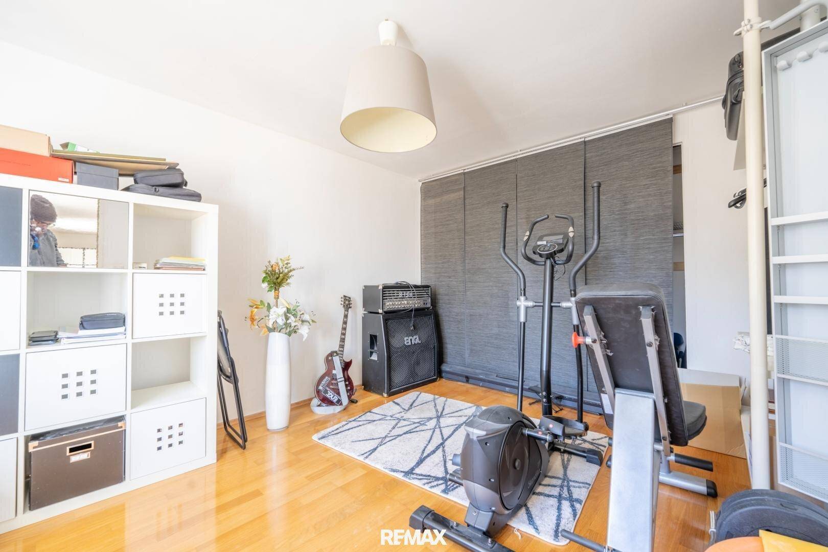 Raum eingerichtet als Fitnessbereich mit verschiedenen Trainingsgeräten und Holzfußboden.