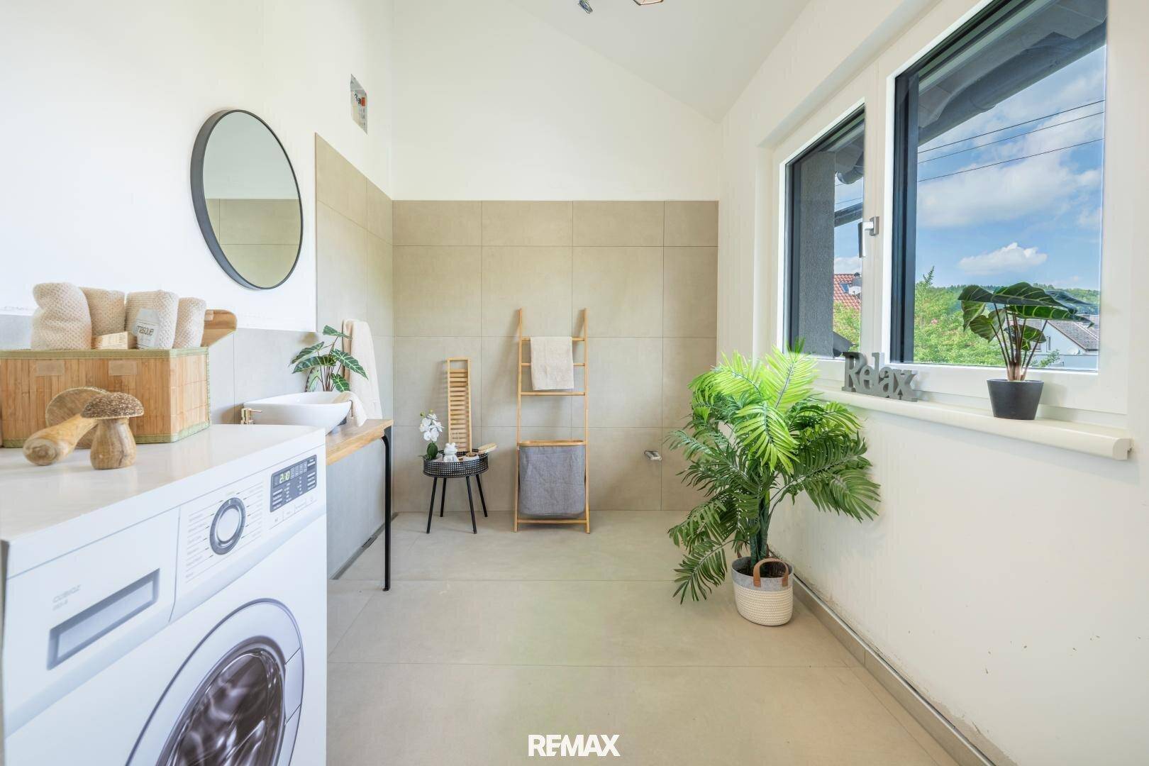 Funktionaler Hauswirtschaftsraum mit Waschmaschine, Waschbecken und großem Fenster.