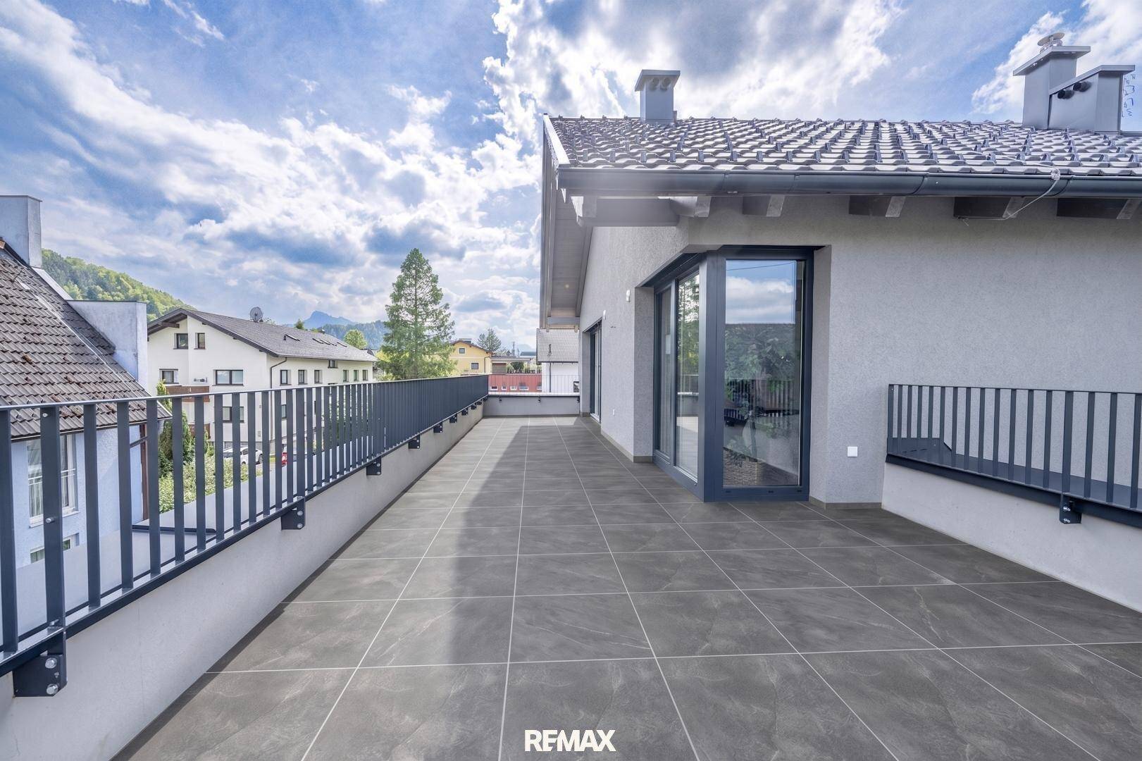 Geräumige Dachterrasse mit modernen Fliesen und Blick auf die umliegende Berglandschaft.