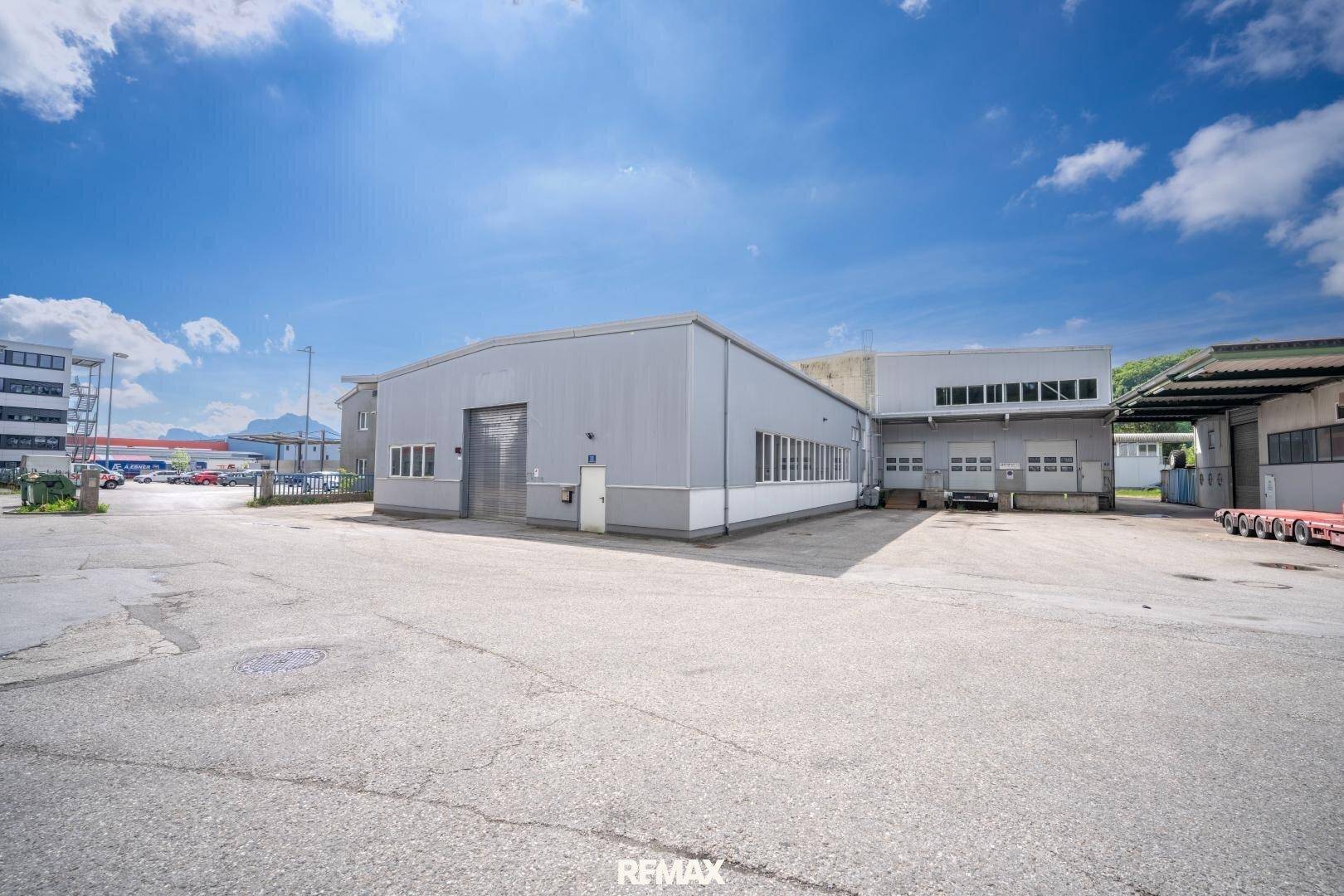 Außenansicht der Industriehalle mit großem Vorplatz und Laderampen unter blauem Himmel.