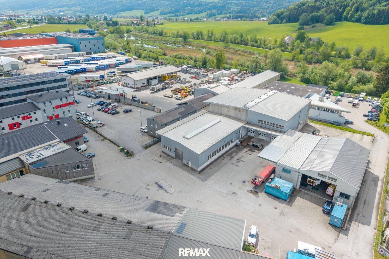 Luftaufnahme des gesamten Industriekomplexes mit mehreren Hallen und Parkflächen in ländlicher Umgebung.