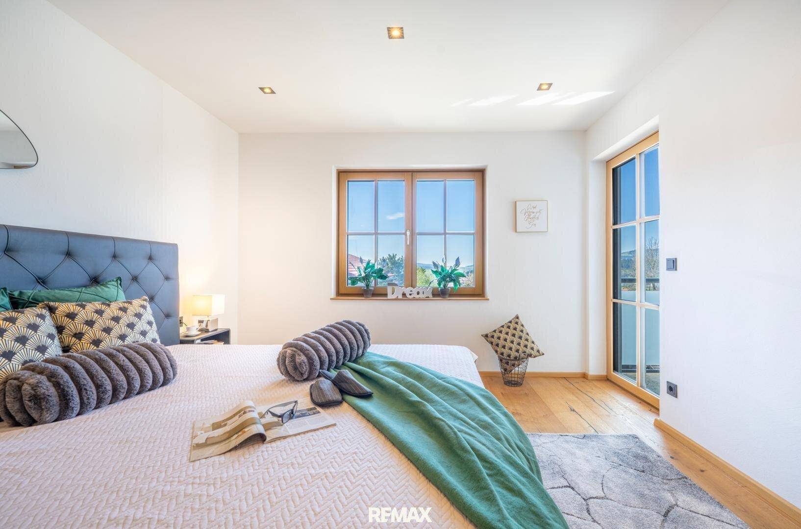 Helles Schlafzimmer mit Doppelbett, Holzboden und Zugang zu einem Balkon.