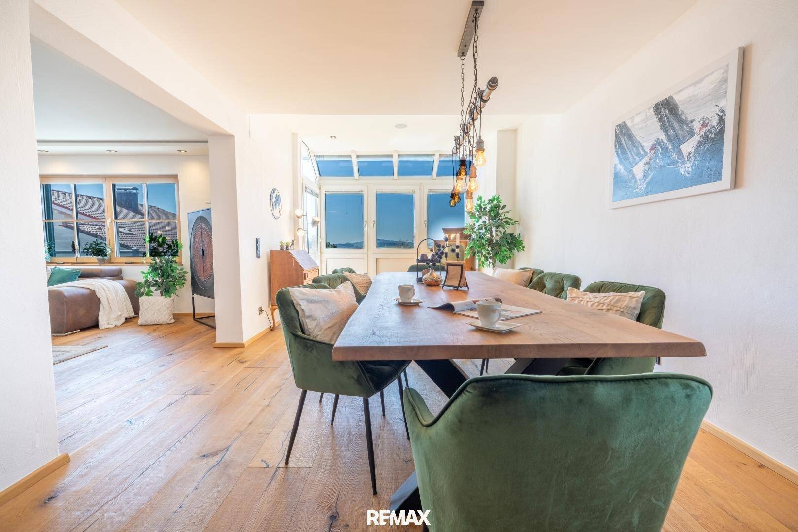 Heller Essbereich mit großem Holztisch, grünen Stühlen und Zugang zu einem Balkon.