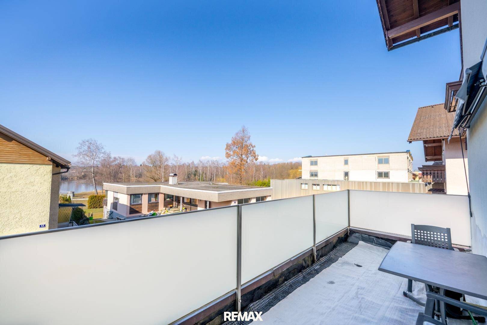 Balkon mit Sitzgelegenheiten und weitem Blick auf den See und die umliegende Landschaft.