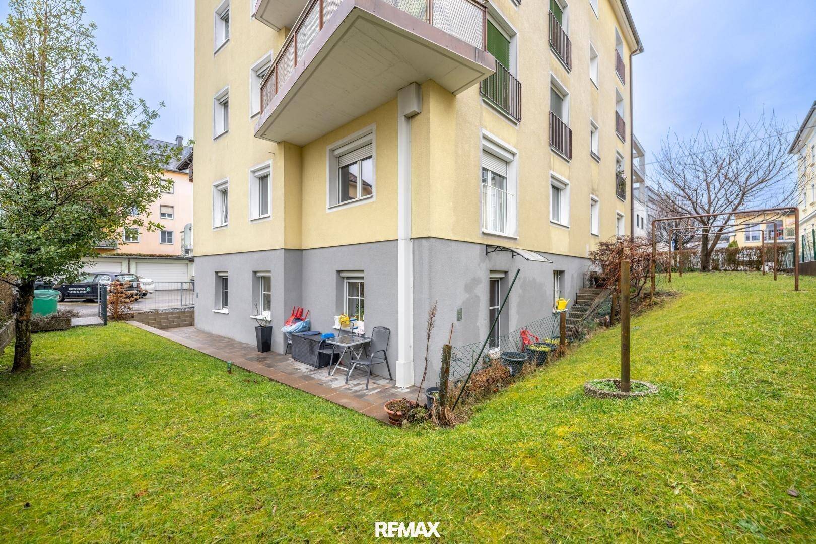 Gepflegter Gartenbereich mit Rasenfläche und kleiner Terrasse am Gebäude.