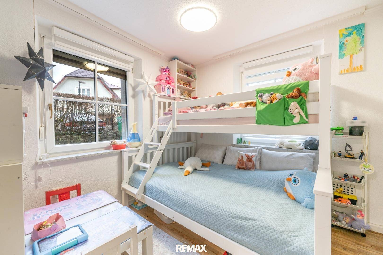 Kinderzimmer mit Etagenbett, Schreibtisch und Fenster mit Blick ins Grüne.