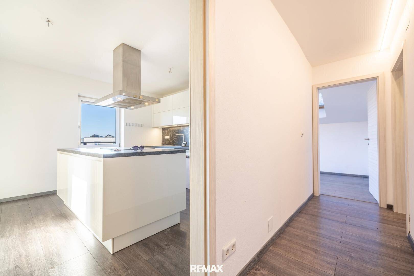 Heller Flur mit modernem Laminatboden, der zur Küche und weiteren Räumen führt.