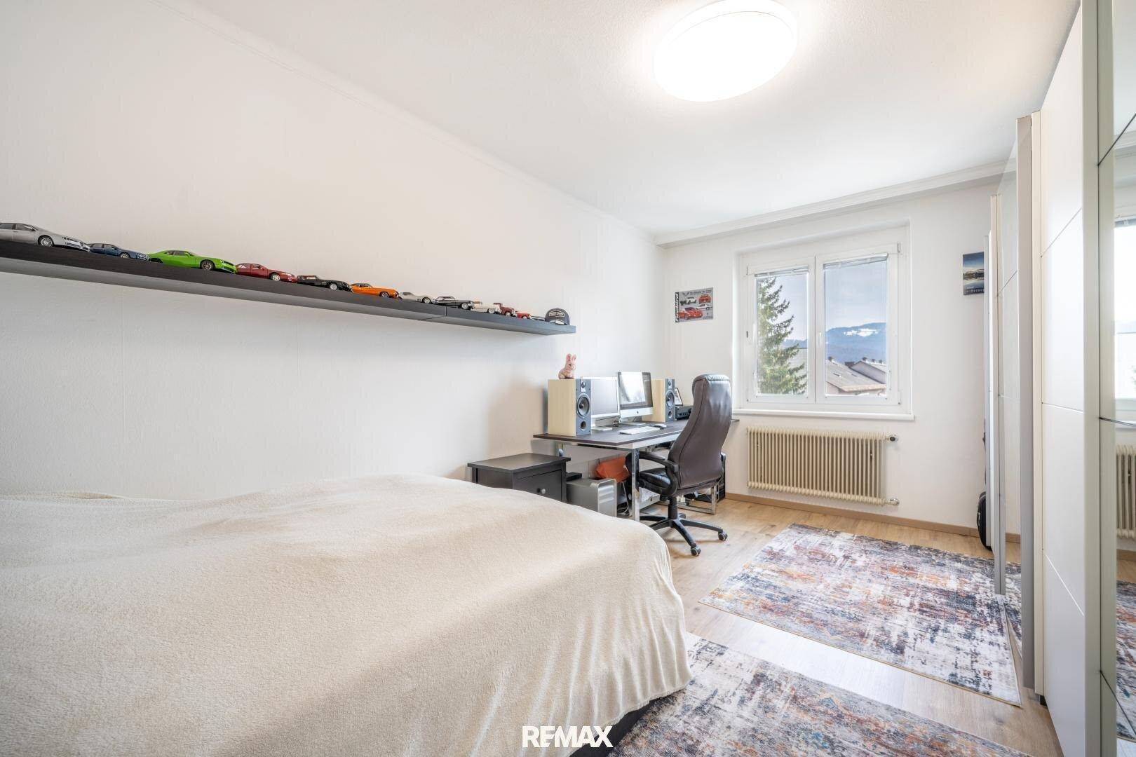 Schlafzimmer mit Schreibtisch, Holzboden und Fenster mit Bergblick.