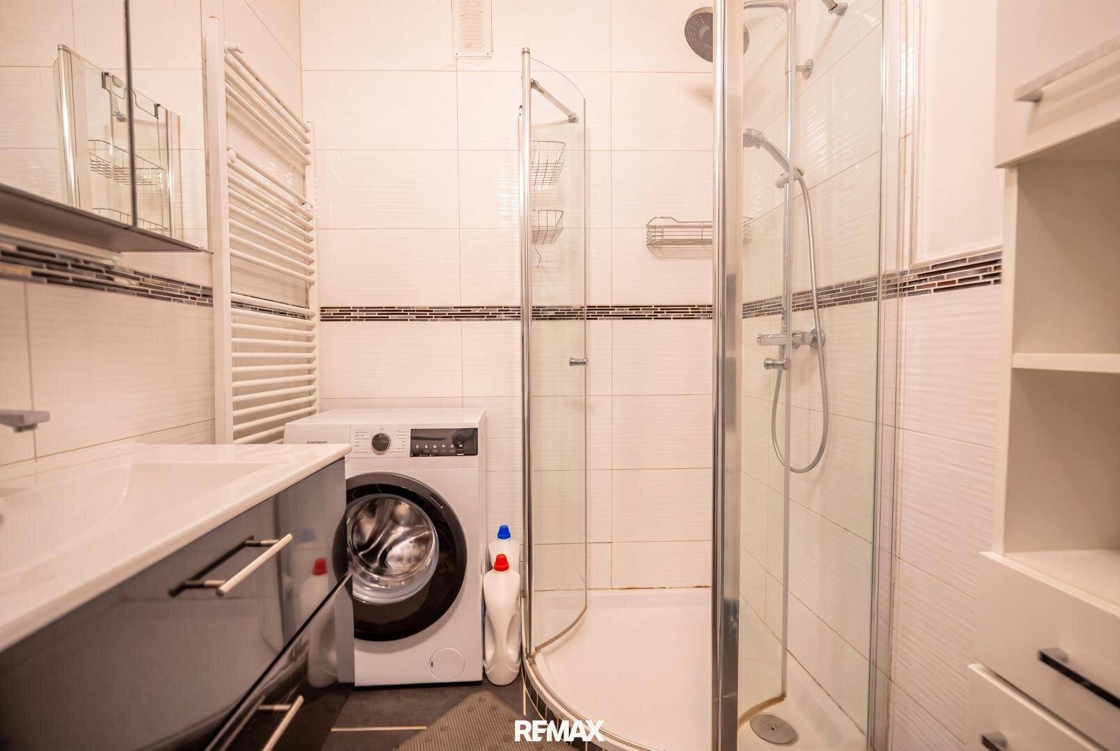 Modernes Badezimmer mit Duschkabine, Waschbecken, Waschmaschine und Handtuchheizkörper.