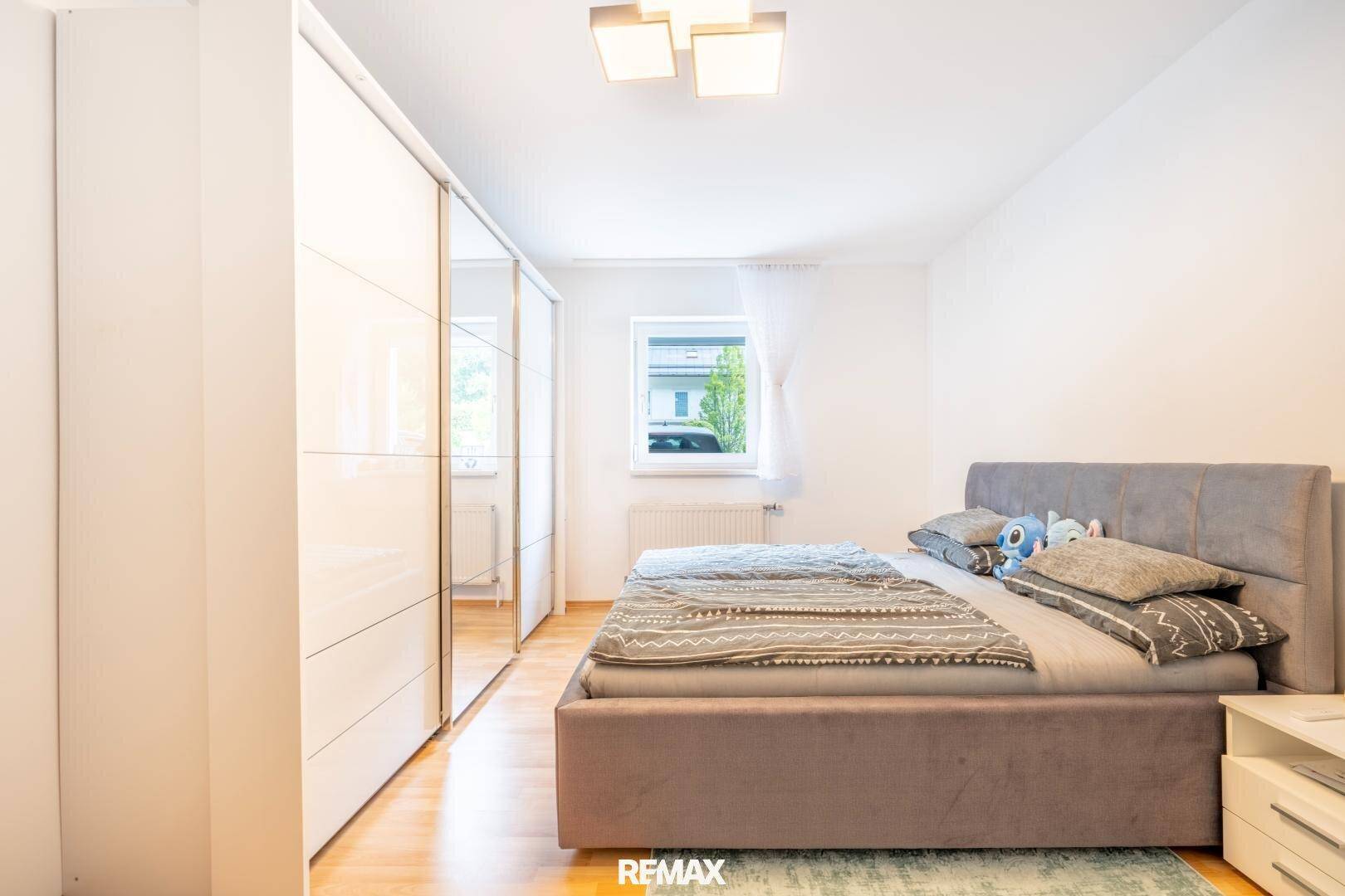 Geräumiges Schlafzimmer mit großem Spiegelschrank, Doppelbett und Holzboden.