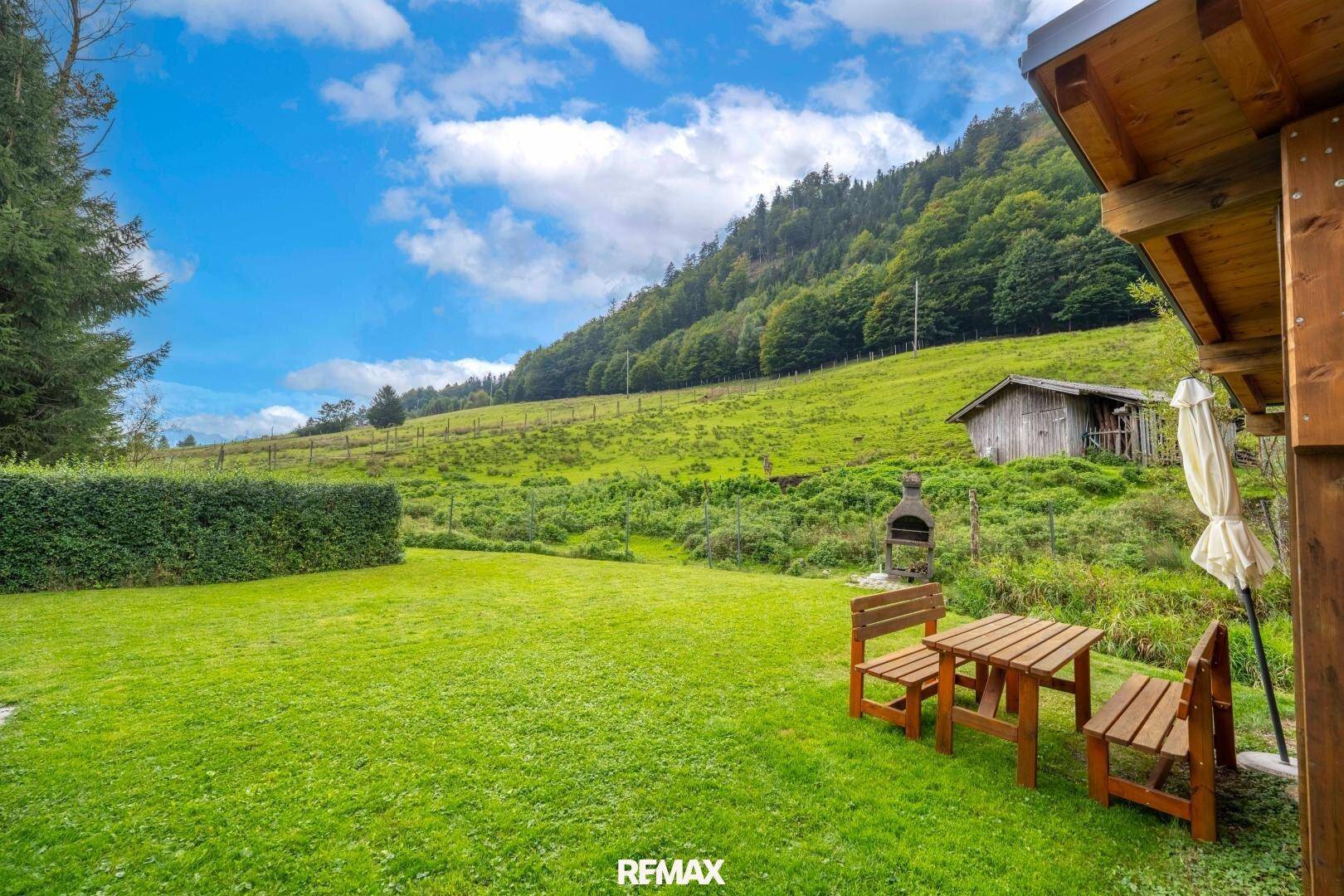 Großer grüner Garten mit Sitzgelegenheiten, Grillplatz und beeindruckendem Bergblick.