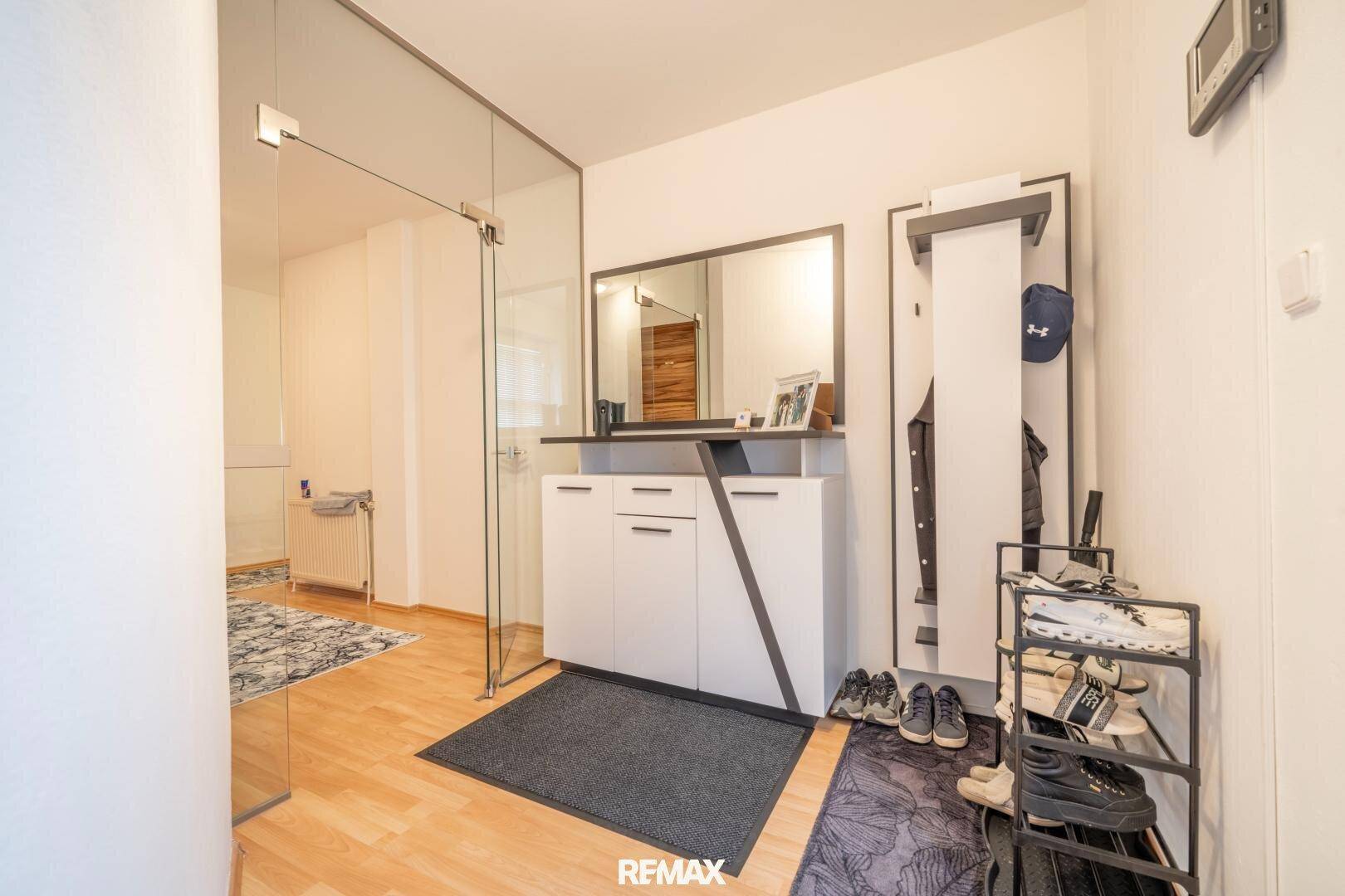 Heller Eingangsbereich mit Garderobe, Spiegel und praktischem Schuhregal.