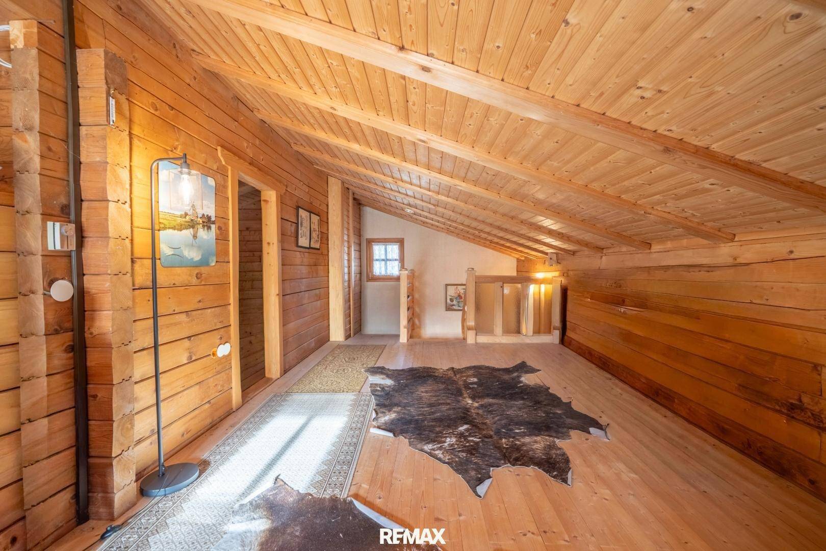 Dachgeschossflur mit schrägen Holzdecken, Holzboden und rustikalen Teppichen.
