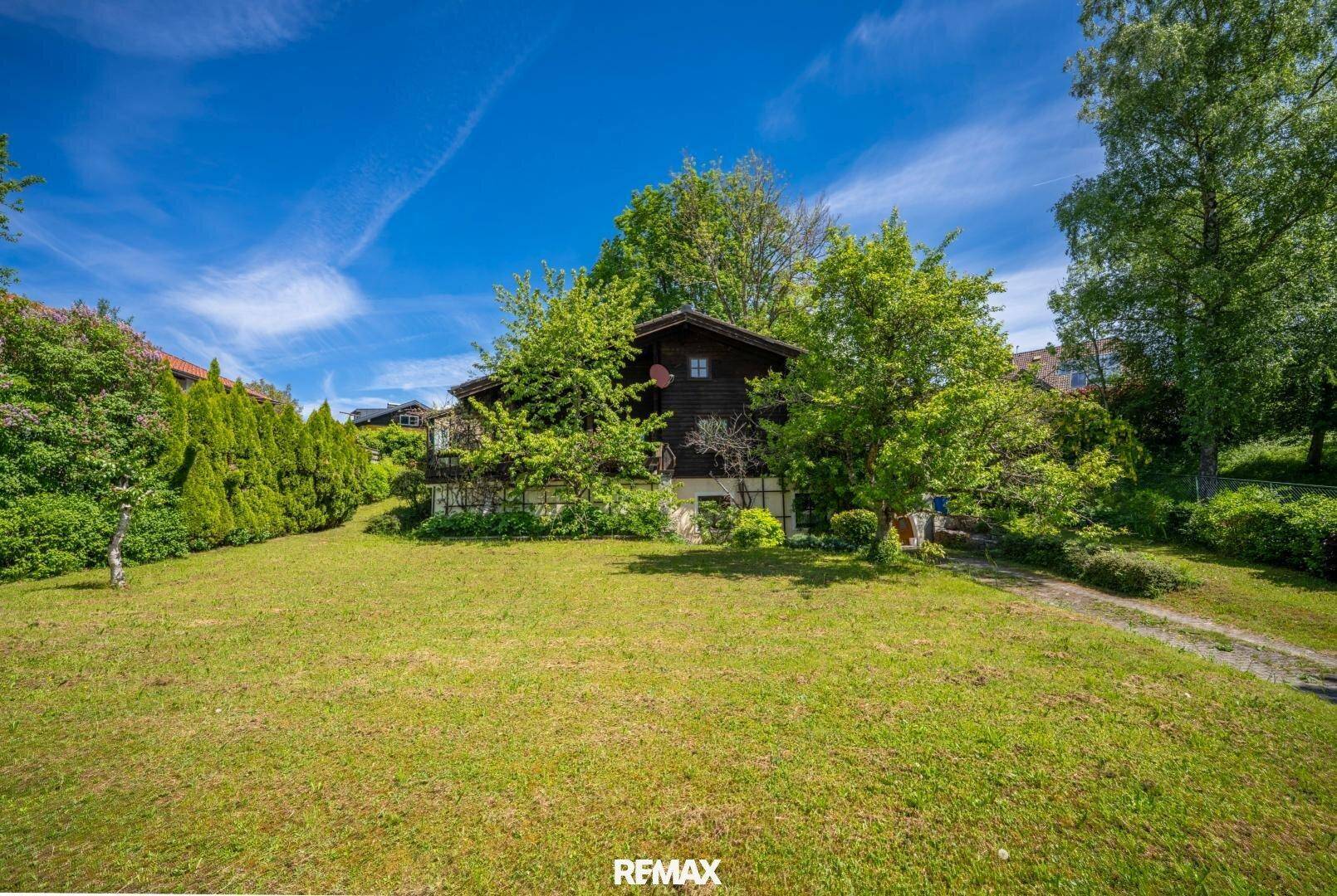 Weitläufiges Grundstück mit einem charmanten Holzhaus und üppiger Vegetation im Sommer.