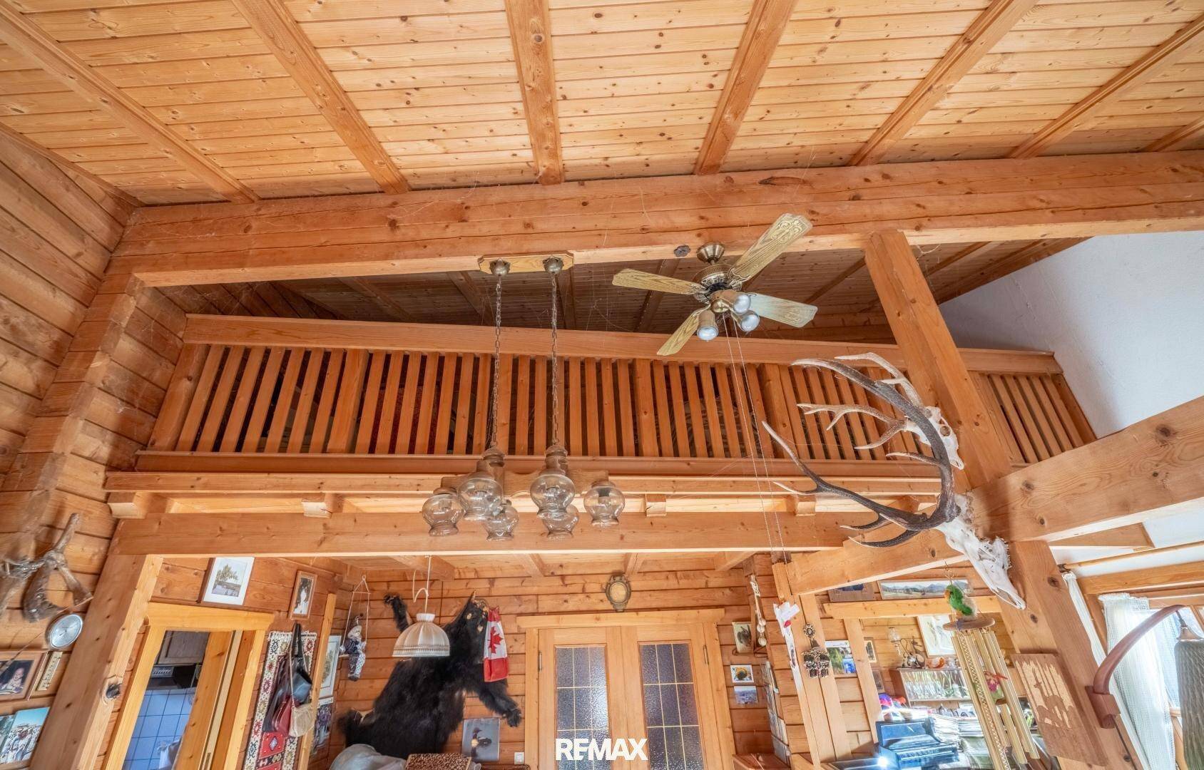 Hohe Holzdecke mit sichtbaren Balken und einem Deckenventilator im Wohnbereich.