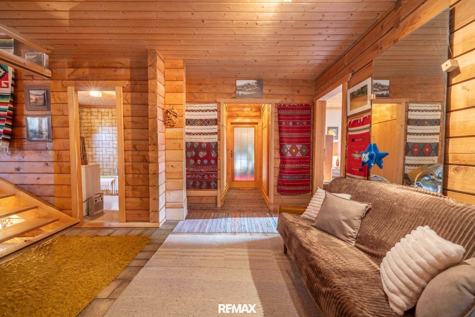 Rustikaler Flur mit Holzwänden, Teppichboden und traditionellen Wandteppichen.