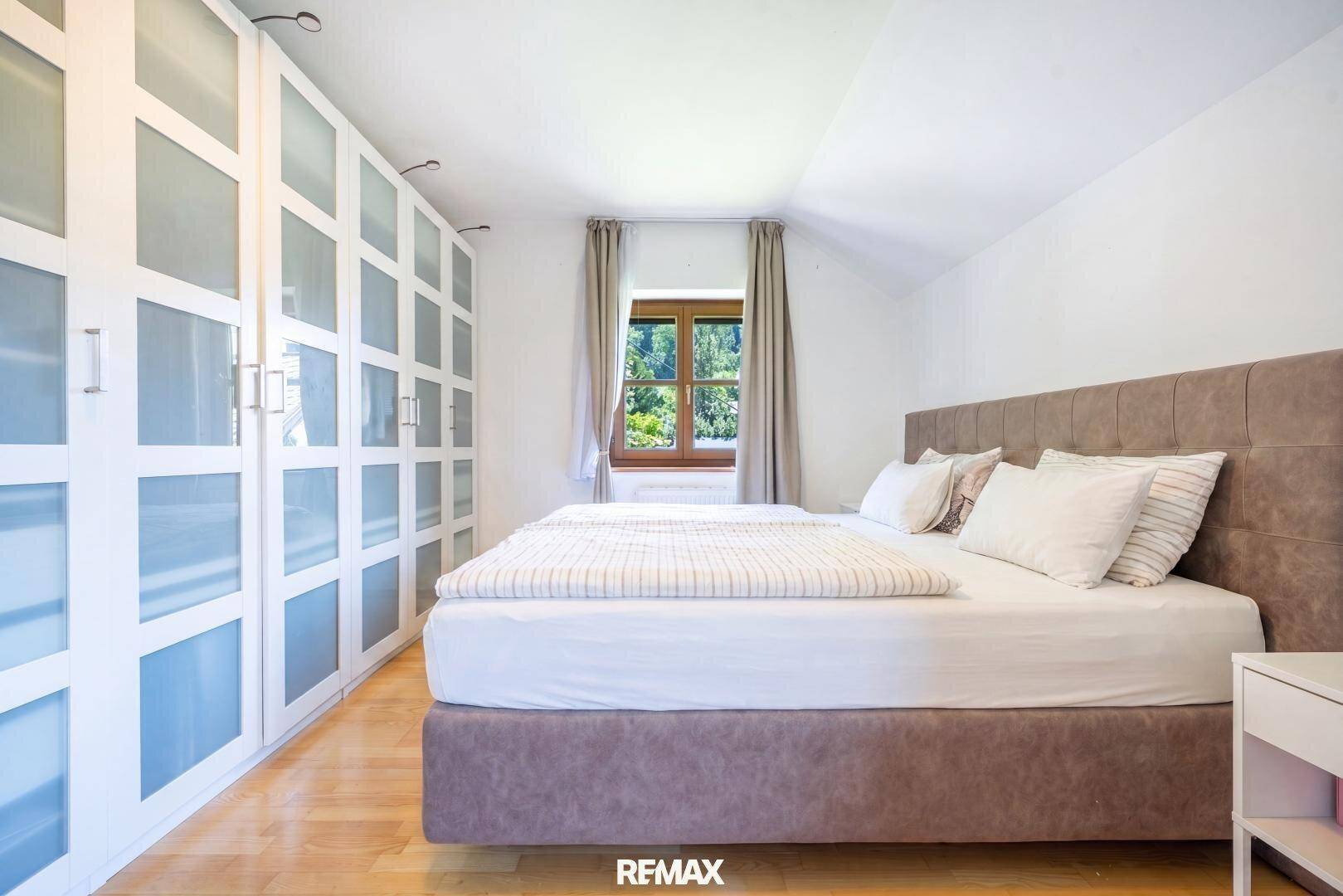 Helles Schlafzimmer mit großem Bett, Einbauschränken und Holzboden.