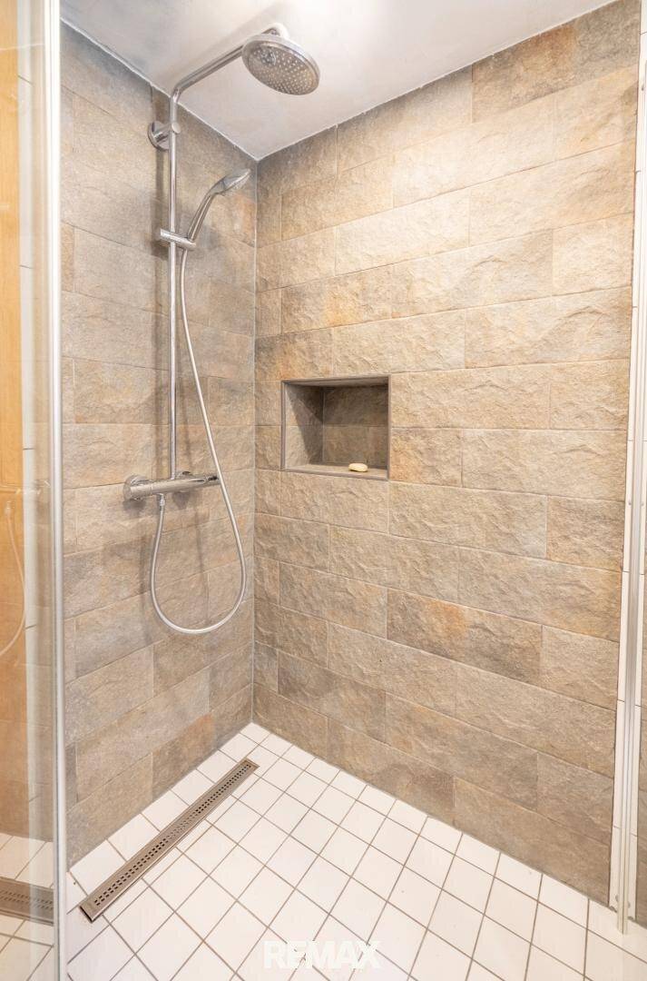 Moderne begehbare Dusche mit Fliesen und Regenbrause.
