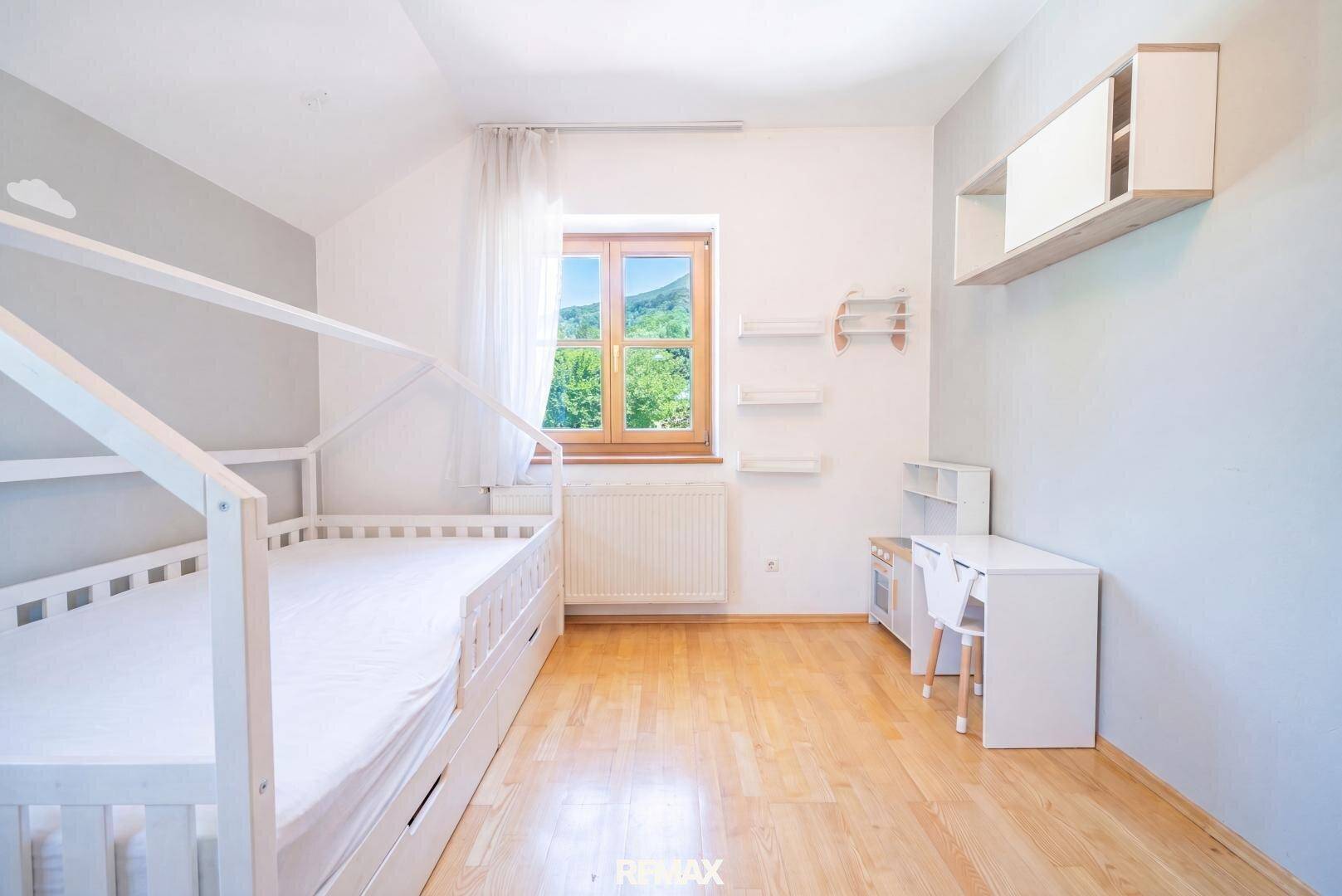 Kinderzimmer mit Holzboden, hellem Design und Blick ins Grüne.